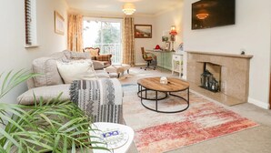 A cozy living room with a fireplace, a sofa, a coffee table, and a dining table. - Windermere house with Lake View, 3 bed 3 bath, dog friendly with ample parking (Bowness-on-Windermere)