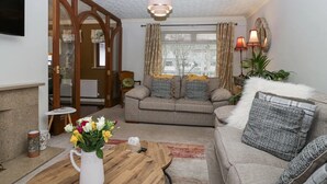 A cozy living room with a sofa, a coffee table, and a fireplace. - Windermere house with Lake View, 3 bed 3 bath, dog friendly with ample parking (Bowness-on-Windermere)