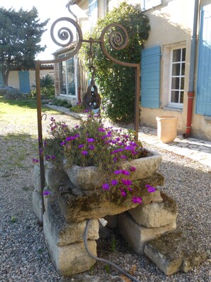 A stone planter with purple flowers and a metal spiral structure. - House with garden (Avignon)