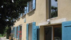 Un edificio con contraventanas azules, un camino de piedra y plantas en macetas.