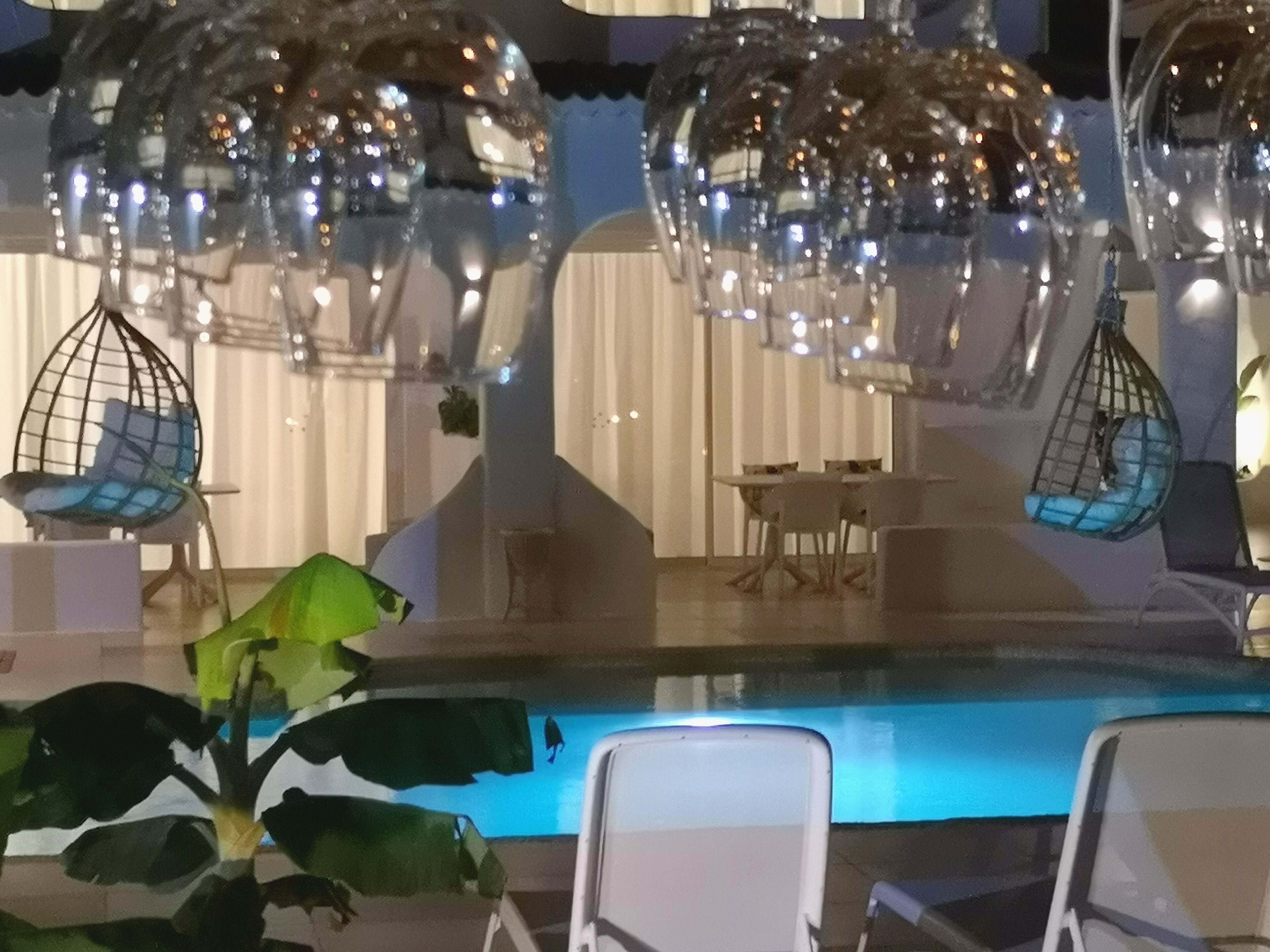 A pool area with hanging chairs and a table.