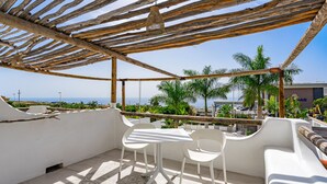 A terrace with a table and chairs, overlooking a pool and palm trees. - instant holiday feeling  (Santiago del Teide)