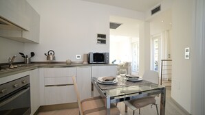 Une cuisine moderne avec une table à manger en verre, des meubles blancs et des appareils électroménagers en acier inoxydable.