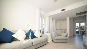 Un salon moderne avec un canapé beige, un fauteuil plus petit et une table basse.
