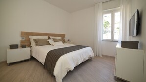 Une chambre à coucher avec un lit, des tables de chevet, une commode et un téléviseur.