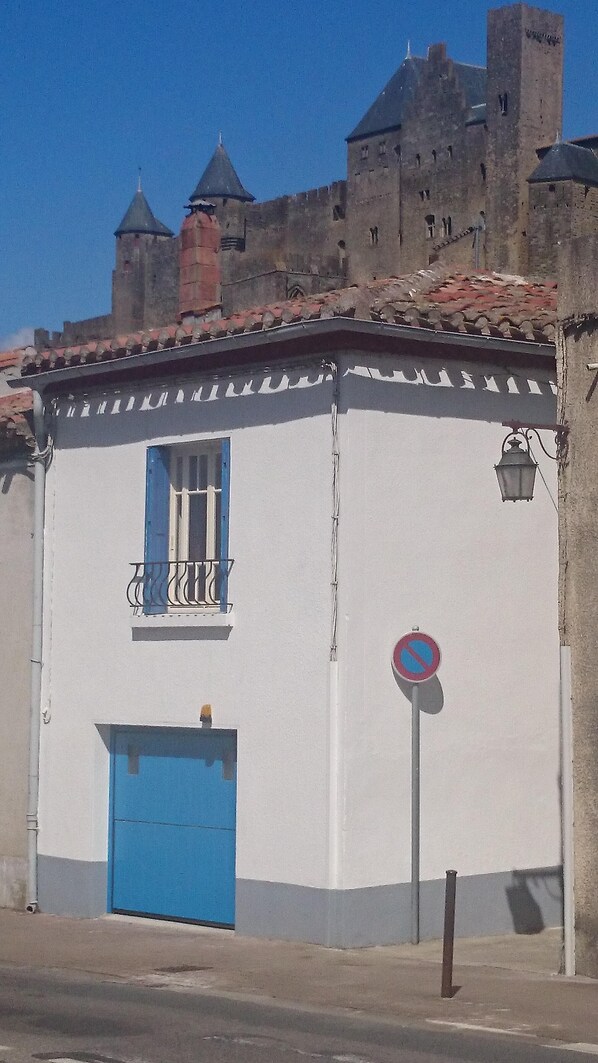 A building with a white facade, a blue door, and a small balcony. - Well-equipped House At Foot of Medieval Cité with Garage, Wifi & 2 Shower rooms (Carcassonne)