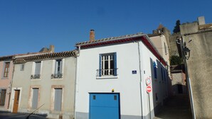 Une rue étroite bordée d’immeubles, avec une porte bleue et un panneau indiquant l’interdiction d’accès.