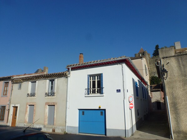 A narrow street with buildings, a blue door, and a no entry sign.