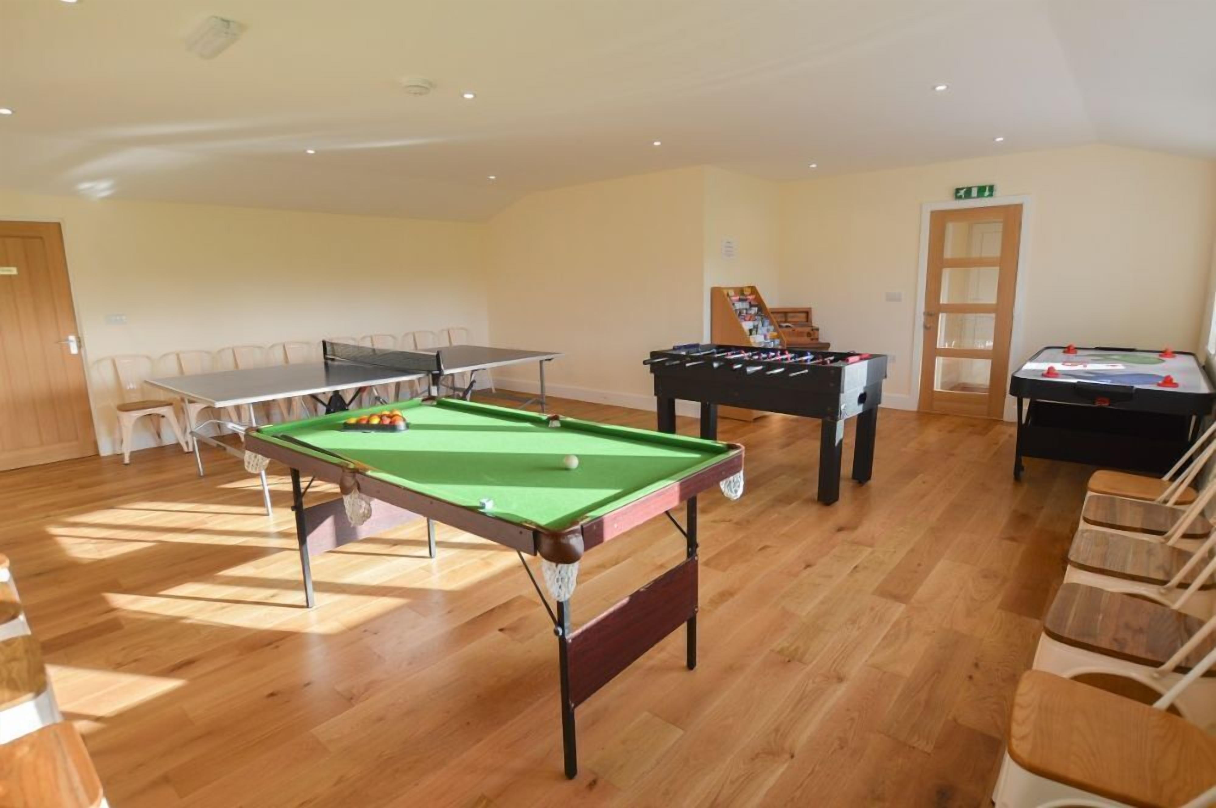 Una sala con mesa de billar, mesa de futbolín y mesa de ping pong.