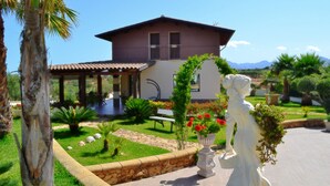 Una casa con un patio, una estatua y un jardín lleno de flores y plantas.