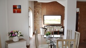 Un salón moderno con una mesa de comedor de vidrio, sofás blancos y una pared de acento de piedra.