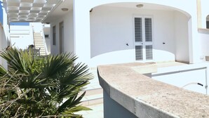A white building with a covered outdoor area and a door with shutters. - GALLIPOLI / MARINA DI MANCAVERSA VILLA TUCHESE 4/5 PLACES 100 MT FROM THE SEA (Marina di Mancaversa-giannelli)