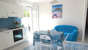 A kitchen with white cabinets, a stove, and a dining area with a table and chairs. - GALLIPOLI / MARINA DI MANCAVERSA VILLA TUCHESE 4/5 PLACES 100 MT FROM THE SEA (Marina di Mancaversa-giannelli)