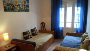 Ein Schlafzimmer mit einem Einzelbett, einem kleinen Sofa, einem Nachttisch und einem Fenster mit Vorhängen.