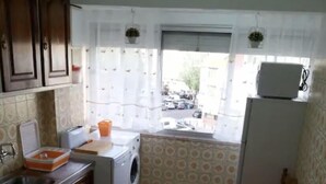 Eine kompakte Küche mit Waschmaschine, Spüle und einer Essecke mit Tisch und Stühlen.