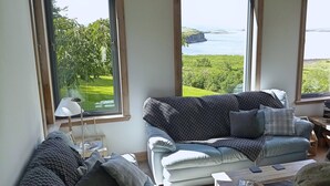 Een woonkamer met een groot raam dat uitzicht biedt op een kustlandschap.