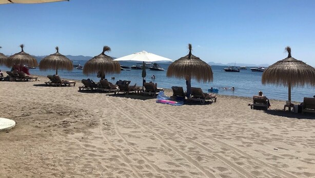 A beach with sun loungers and thatched umbrellas, a clear sky, and boats in the water. - Luxury 6-person villa with swimming pool, sunroof near the beach and golf courses (San Pedro del Pinatar)