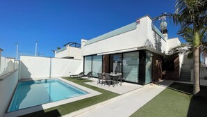 A modern house with a swimming pool, a patio with outdoor furniture, and a palm tree. - Luxury 6-person villa with swimming pool, sunroof near the beach and golf courses (San Pedro del Pinatar)