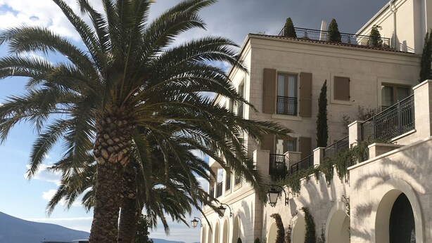 A coastal promenade with a palm tree, a building with arched windows, and a view of the sea. - LUXURY VILLA WITH PRIVATE POOL ON BEAUTIFUL AND ACCESSIBLE LUSTICA PENINSULA (Ðuraševici)