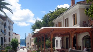 A coastal town with outdoor seating areas, a historic building with a stone facade, and a cannon in the foreground. - LUXURY VILLA WITH PRIVATE POOL ON BEAUTIFUL AND ACCESSIBLE LUSTICA PENINSULA (Ðuraševici)