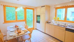 A kitchen with a dining table, chairs, and a refrigerator.