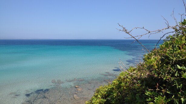 A coastal view with clear turquoise waters and rocky shoreline.