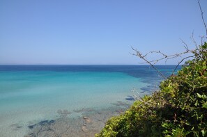 A coastal view with clear turquoise waters and rocky shoreline.