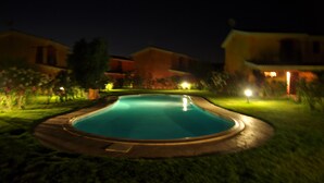 A swimming pool surrounded by well-lit buildings at night.