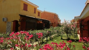 A courtyard with yellow buildings, a satellite dish, and pink flowers.