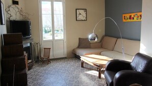 Ein Wohnzimmer mit Sofa, Couchtisch, Fernseher und Kamin.