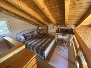 A cozy cabin-style bedroom with a wooden ceiling, a bed with a fur blanket, a desk with a lamp, and a chair. - Chalet l'Ange - La Tzoumaz, 4 Vallees (La Tzoumaz)