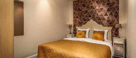 A hotel room with a large bed, a geometric-patterned wall, and a wooden door.