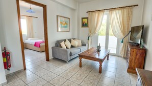 A living room with a sofa, a wooden coffee table, a television, and a fire extinguisher. - ☀️Villa Varvara❤️Almyrida⛱️ 350m from Sea❗️No car needed ❗️Samaria Gorge - For Free (Almyrida)