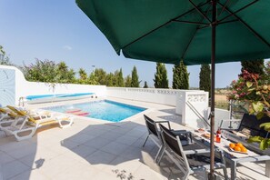 A pool area with lounge chairs, a table with food and drinks, and a view of the landscape. - CoolHouses Algarve Lagos | Casa Redonda (Lagos)