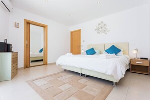 Een moderne slaapkamer met een bed, nachtkastjes, een dressoir en een spiegel.