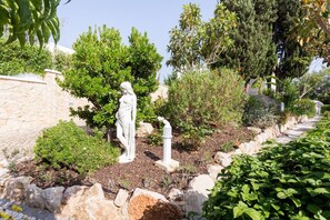 A garden with a white statue, stone wall, and various plants. - CoolHouses Algarve Lagos | Casa Redonda (Lagos)
