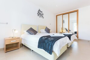 A modern bedroom with a large bed, bedside tables, and a mirror.