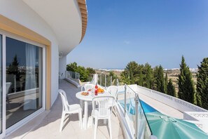 Een balkon met een tafel en stoelen, een zwembad en uitzicht op het landschap.