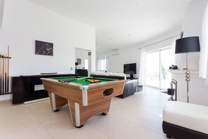 A modern living room with a pool table, a sofa, a television, and a lamp. - CoolHouses Algarve Lagos | Casa Redonda (Lagos)