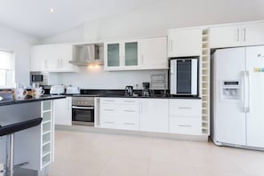 Une cuisine moderne avec des meubles blancs, un plan de travail noir, des appareils en acier inoxydable et un réfrigérateur encastré.