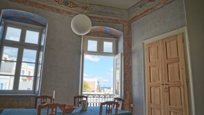 A room with a dining table, chairs, a window with a view, and a door.