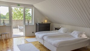 Een slaapkamer met een groot bed, houten vloeren, een klein bureau en een raam met uitzicht op de omgeving.