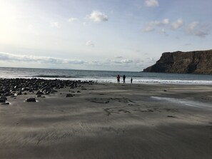 A beach with large rocks in the foreground, a cliff on the right, and a calm sea. - Traditional Croft House with garden. Ample parking and central location. (Isle of Skye)