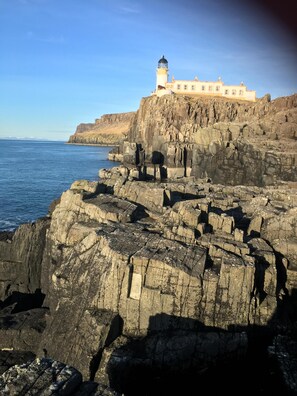 A coastal building with a lighthouse on a rocky cliff, overlooking the sea. - Traditional Croft House with garden. Ample parking and central location. (Isle of Skye)