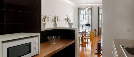 A modern kitchen with a white microwave, wooden countertop, and potted plants.