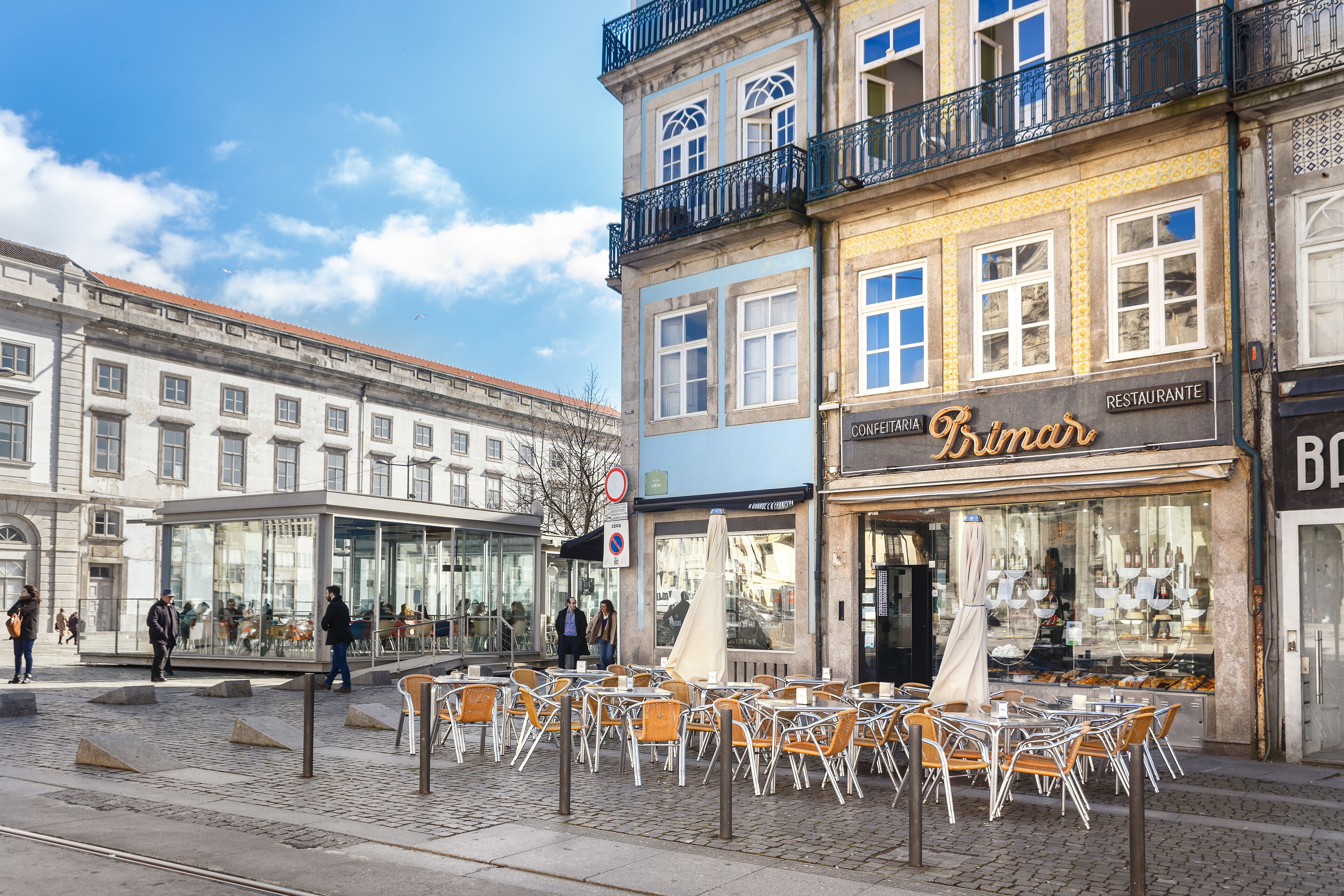 Eine Straße mit Außenbestuhlung, einem Café und einem Restaurant.