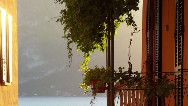 Un balcon avec vue sur la mer, une chaise et une plante suspendue.