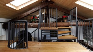 Un escalier en bois avec des rampes en métal menant à une mezzanine dotée de lucarnes.