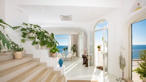 A modern interior with a staircase leading to a balcony with a sea view.
