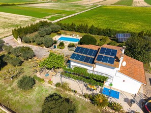 A house with solar panels, a swimming pool, and a garden.